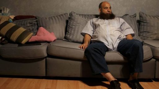 Mohamed Bzeek, who takes in foster children who are ill, sitting on living room couch