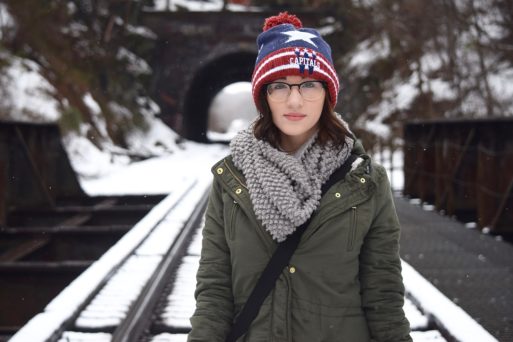 Teenager standing on railroad track with winter clothes on
