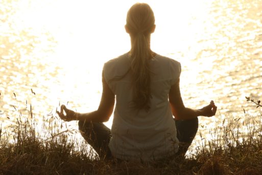 Woman meditating near lake part of integrative therapies