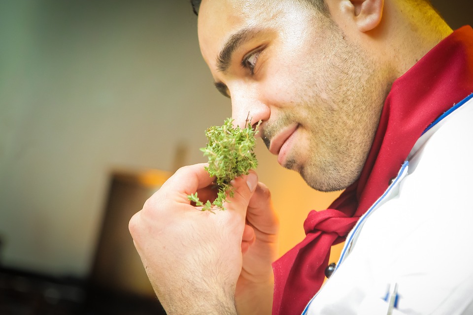 A man holds herbs up to his nose to identify their scent