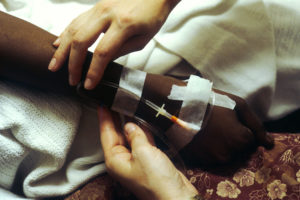 A doctor holds a patient's arm and gives the patient chemotherapy treatment