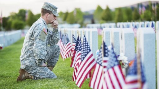 A soldier kneels at the graves of fallen comrades Like Father Like Son
