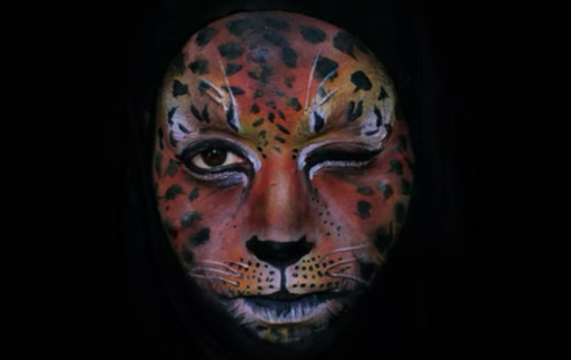Emma Allen winking and wearing orange face paint that looks like a jaguar's face in her movie about the circle of life