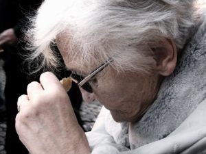 Elderly woman staring down to symbolize dementia