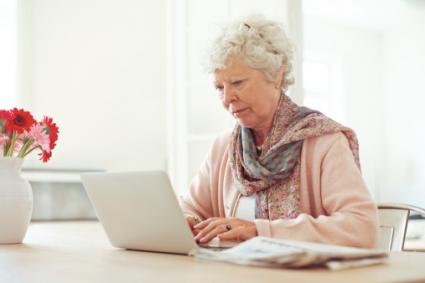 An elderly woman at her laptop could be a victim of elder abuse
