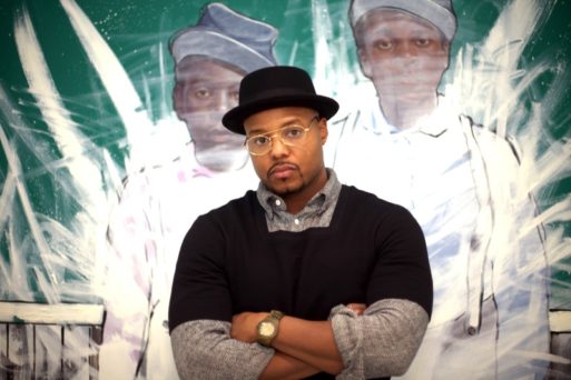 Picture of Titus Kaphar in front of one of his pieces
