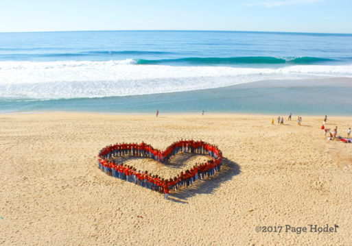 People gathered on the beach in the form of a heart