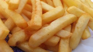 A pile of french fries sitting on a plate, which have been linked to fried potatoes and early death