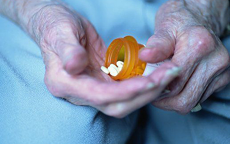 Closeup of elderly person holding a bottle of pills demonstrates polypharmacy