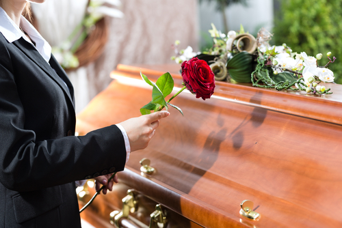 Someone holds a rose up to a coffin as part of a memorial for medical cadavers