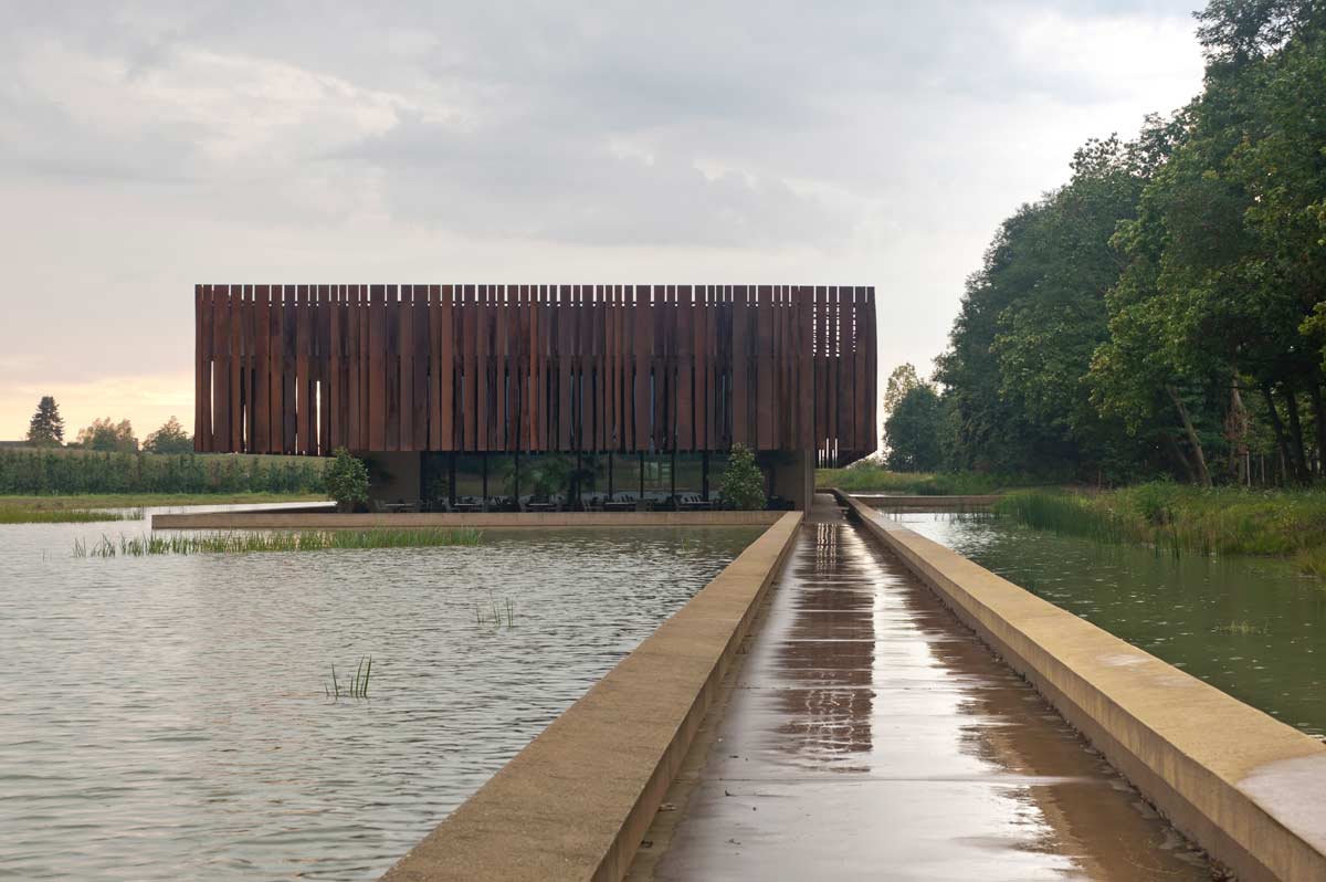 A photo of Hofheide Crematorium, featuring a long line of metal pieces lined up next to each other on the side of the building