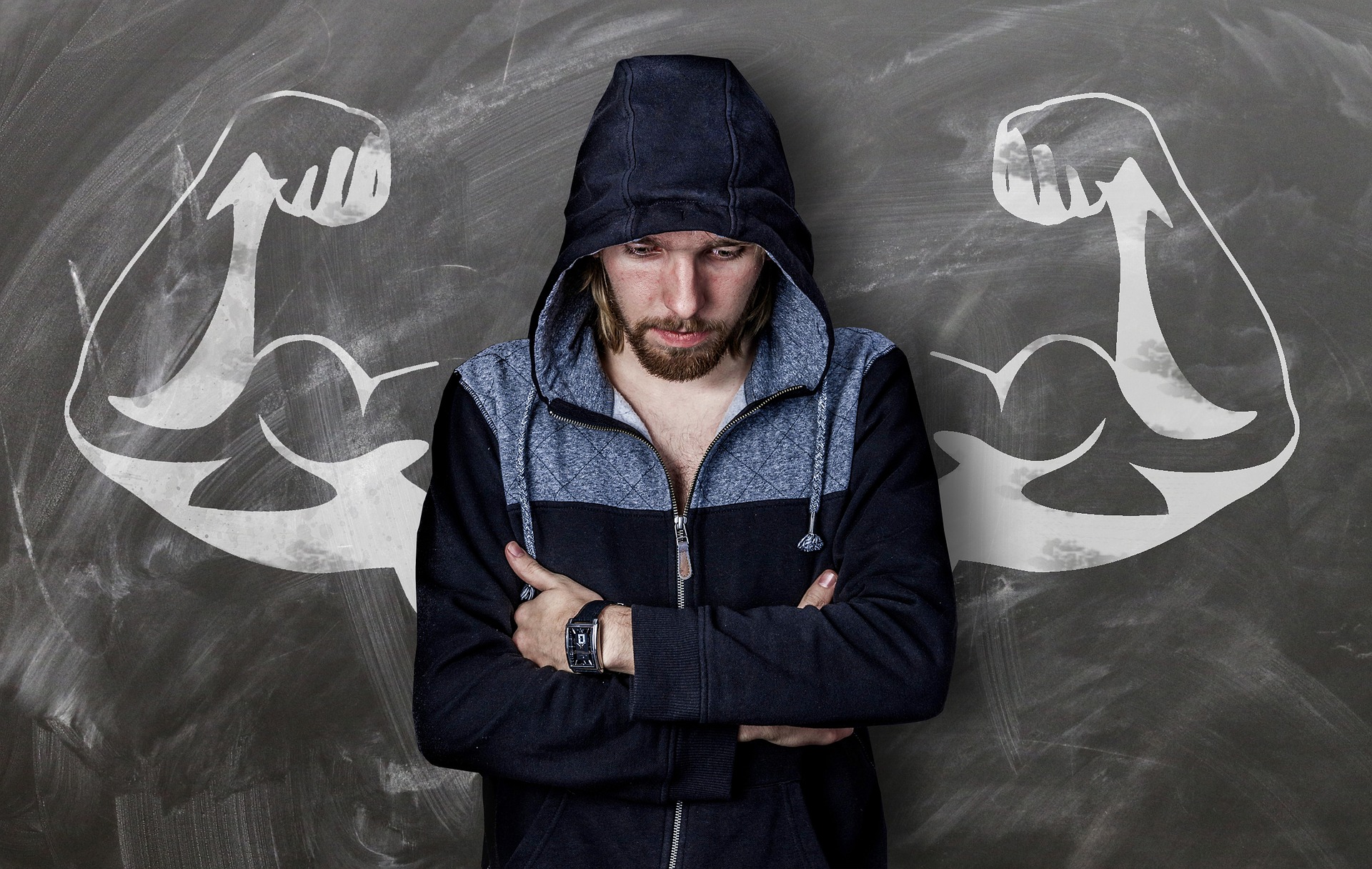 Man standing against a wall that has flexing arms spray painted on symbolizing inner strength.