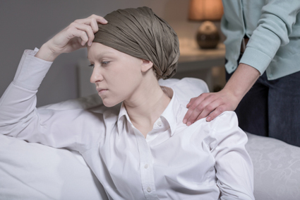 Female cancer patient in a head scarf looking stressed because of her illness
