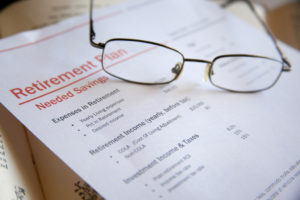 A pair of reading glasses sitting on top of a stack of retirement planning paperwork