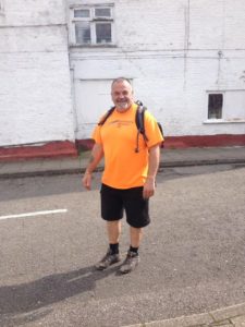 Steve Boryszczuk in the street with hiking gear walking in memory of his deceased wife 