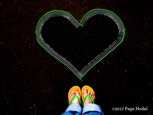 Heart made of nails on black background with sandaled feet 