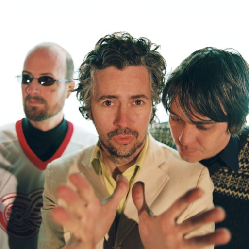 Portrait of The Flaming Lips with Wayne Coyne, who wrote "Do You Realize??," at the front with hands pointing towards the camera