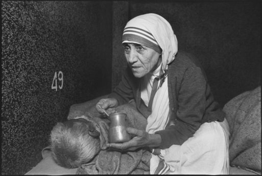 Mother Theresa feeding a sick person in bed