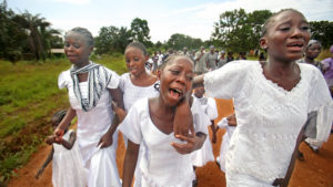 Photo of Liberian children walking and wearing white clothes during a funeral