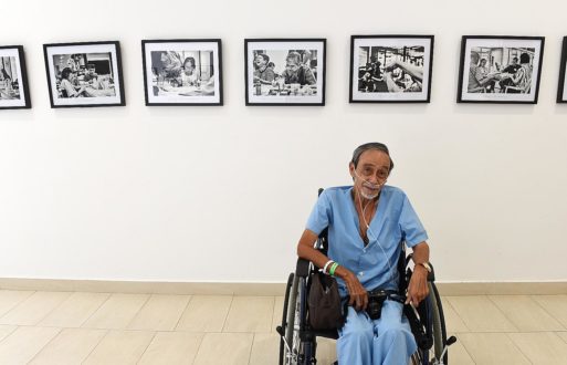 Alan Lee sits in his wheelchair in front of photos of hospice life
