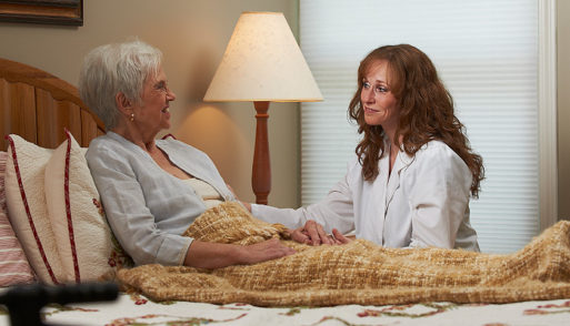 Elderly woman and nurse holding eachother's hands in a hospice center