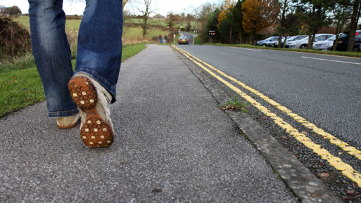 A person walking slowly along the side of the road; scientists have linked walking speed and heart disease