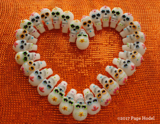 Heart made of Halloween candy with skulls on an orange brackground