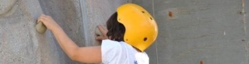 A child climbs a rock wall at Kids Camp