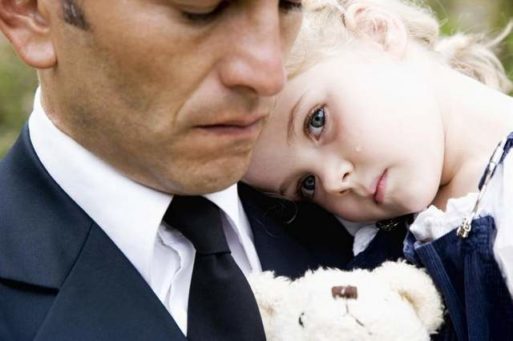 A little girl in her father's arms at a funeral