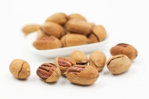 Mix of unopened and partially opened pecans against a white background