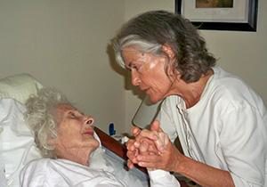 Irene Smith holds a patient's hand in a hospice facility demonstrating touch awareness
