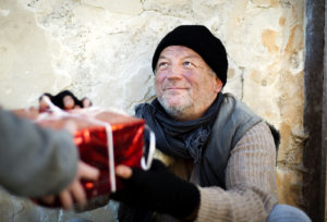 A person giving a Christmas present to a homeless man