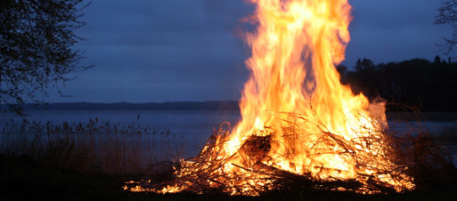 A brightly burning fire by the side of a lake in the dark
