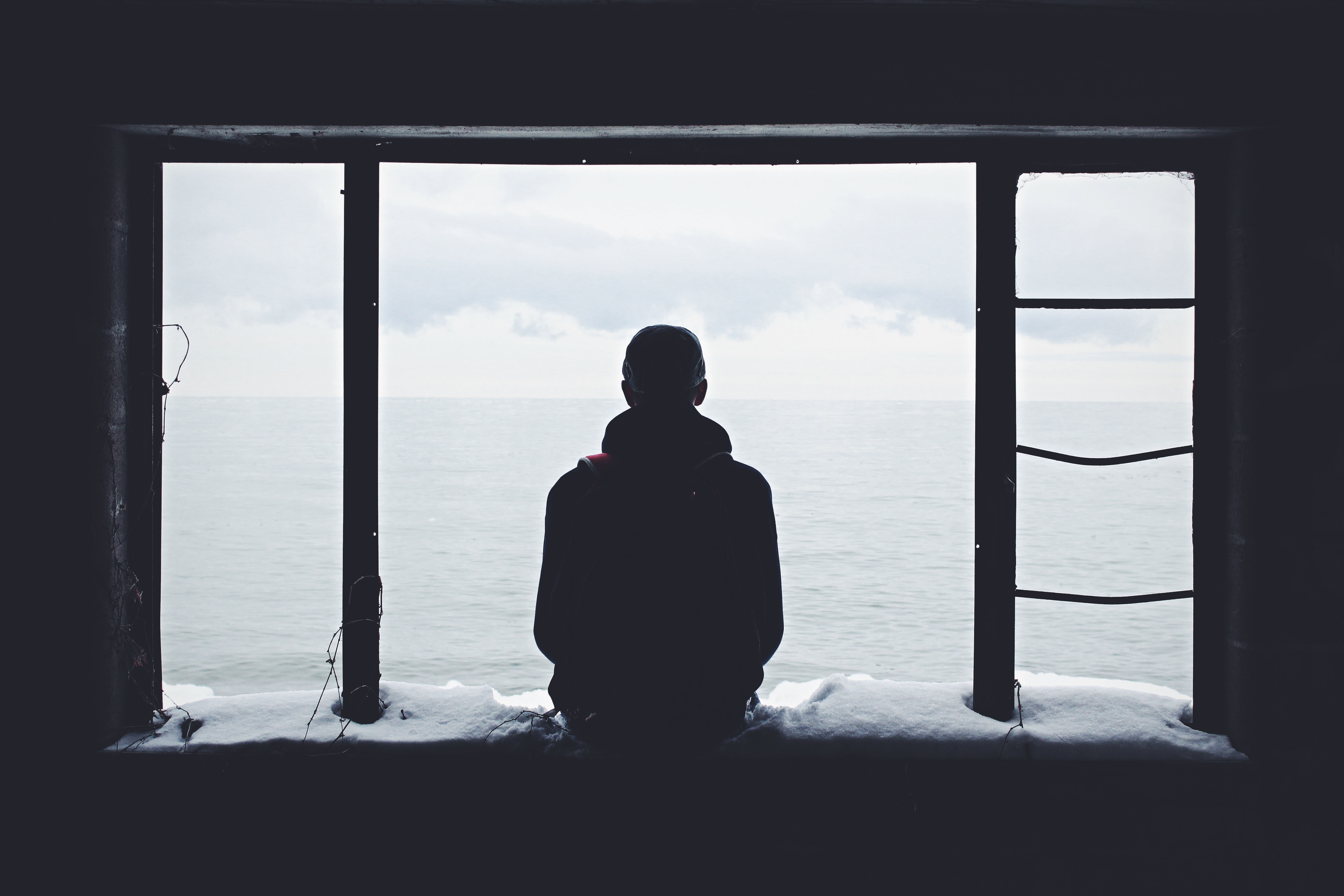 Person staring out of a window alone, contemplating death with dignity