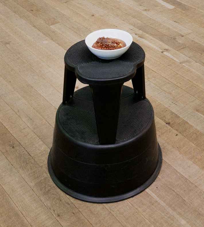 Photo of a footstool with a bownl of honeycomb placed on top, part of Damien Hirst's art installation "Pharmacy"