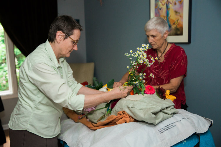 Two women preparing a bed for a body during a home funeral