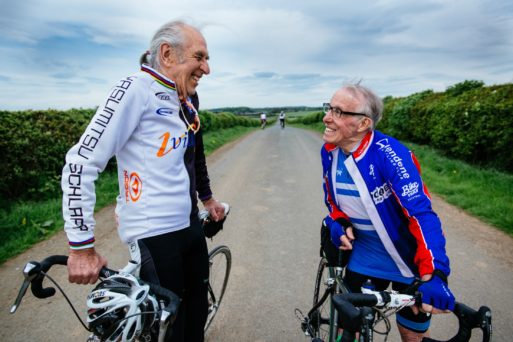 Two elderly cyclists in cycling gear enjoy the benefits of exercising