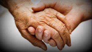 someone holding the hand of an elderly person who wants access to medical aid in dying 