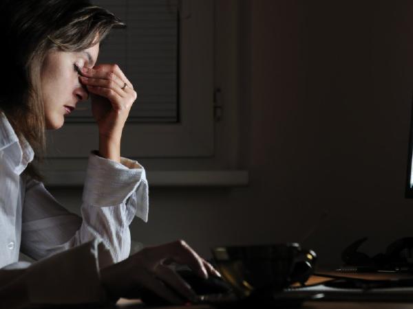 Woman clenching nose appearing tired while on computer