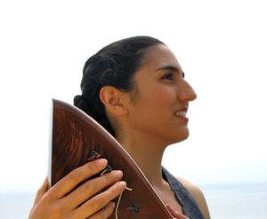 Portia Diwa holding her harp on which she plays healing harp music