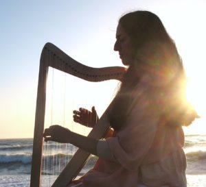 Photo of Portia playing the healing harp at the ocean