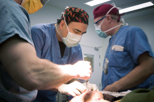 A male nurse attends to a patient in the operating room.