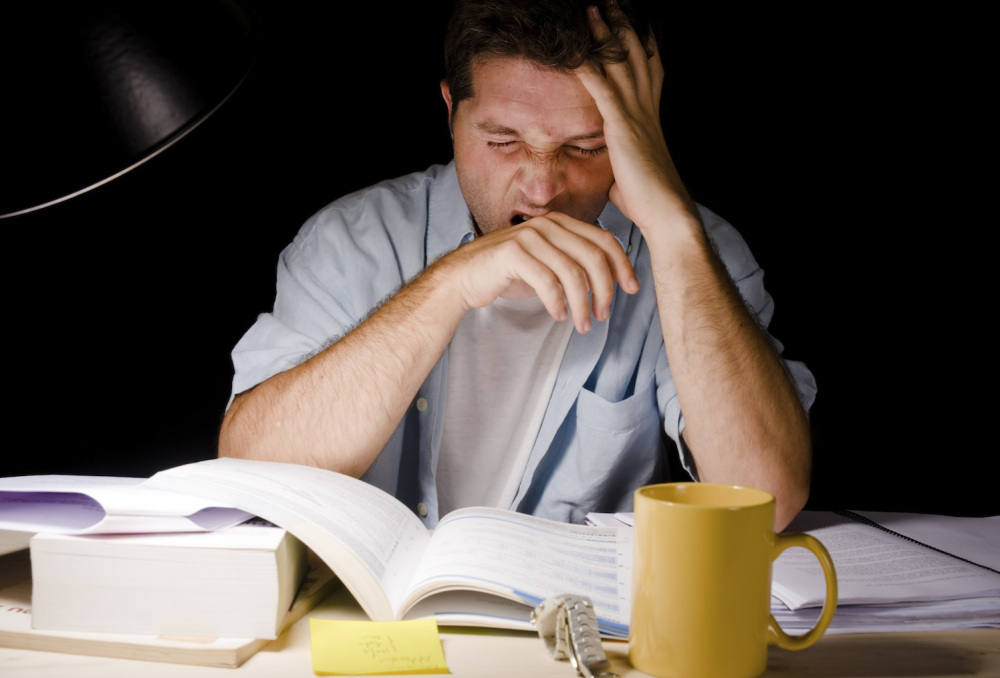 Man yawning while sitting at desk studying