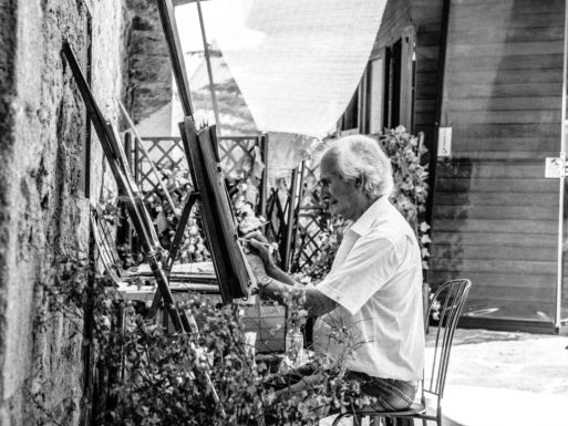 A black and white image of an elderly man painting as a part of active aging