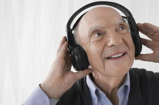 Elderly man listening to music via headphones and smiling using Music & Memory iPod
