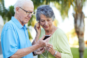 Elderly couple listening to music on an mp3 player like the ones provided by Music & Memory