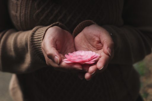 image of hands holding a flower creating new traditions in memorium