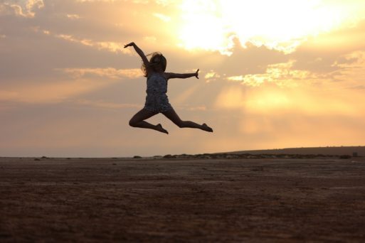 Woman leaping into the air on a beach at sunset