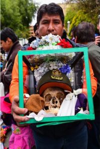 Man holding glass display case of ñatita skull