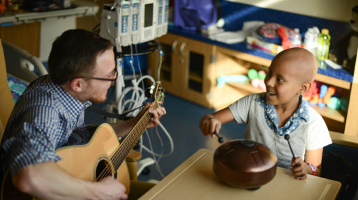 Child getting music therapy and playing a drum